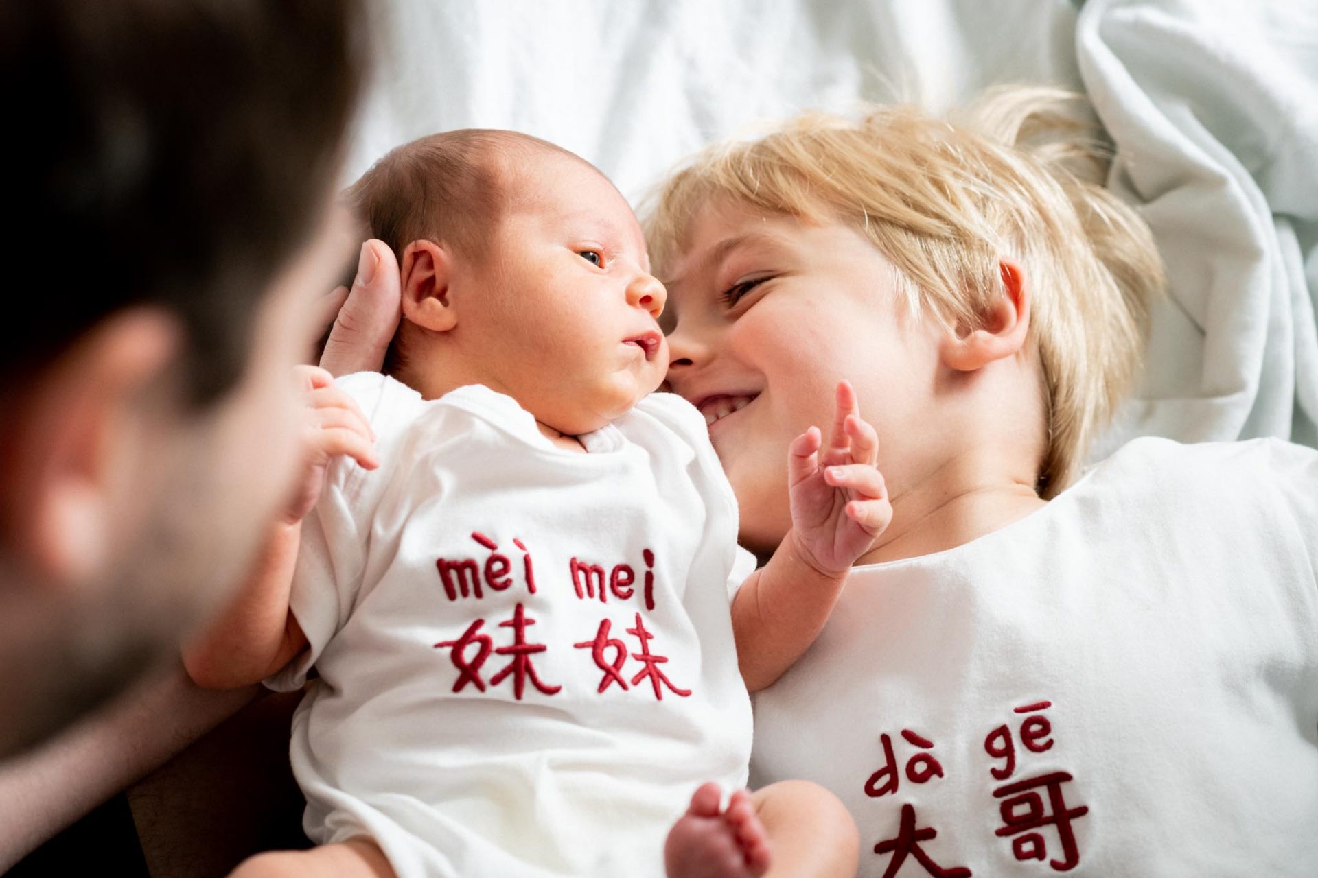 Big brother smiling at his newborn sister, newborn photoshoot